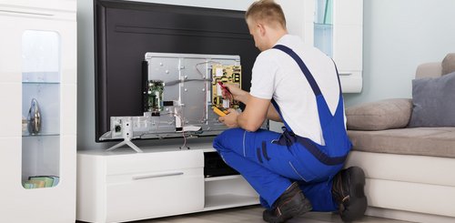 Ein Elektroniker der einen Fernseher repariert in einem Wohnzimmer